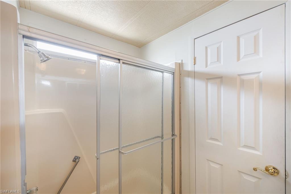 21 San Lu Rue Avenue, Unit 21 Naples, FL 34104 - Photo 19 of 33 a bathroom with a glass shower door