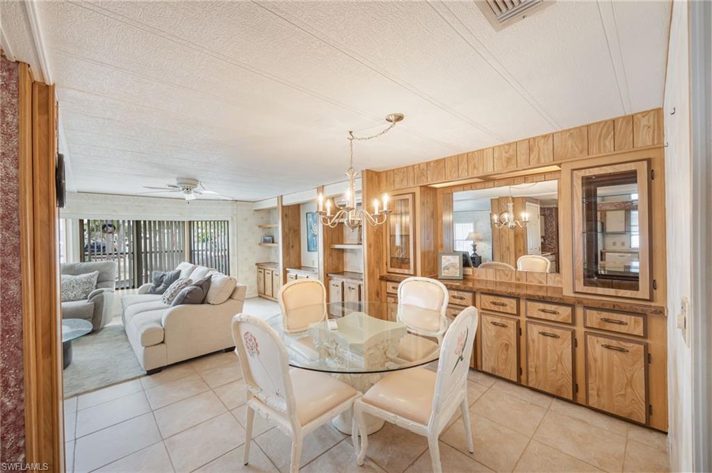 21 San Lu Rue Avenue, Unit 21 Naples, FL 34104 - Photo 4 of 33 a living room with furniture a chandelier and a dining table