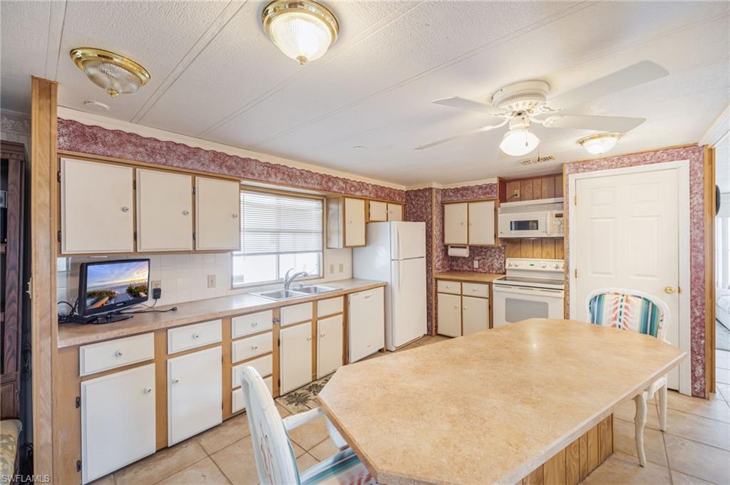 21 San Lu Rue Avenue, Unit 21 Naples, FL 34104 - Photo 8 of 33 a kitchen with kitchen island a sink appliances and cabinets