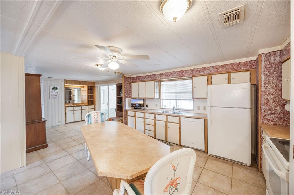 21 San Lu Rue Avenue, Unit 21 Naples, FL 34104 - Photo 9 of 33 a large white kitchen with a window and refrigerator