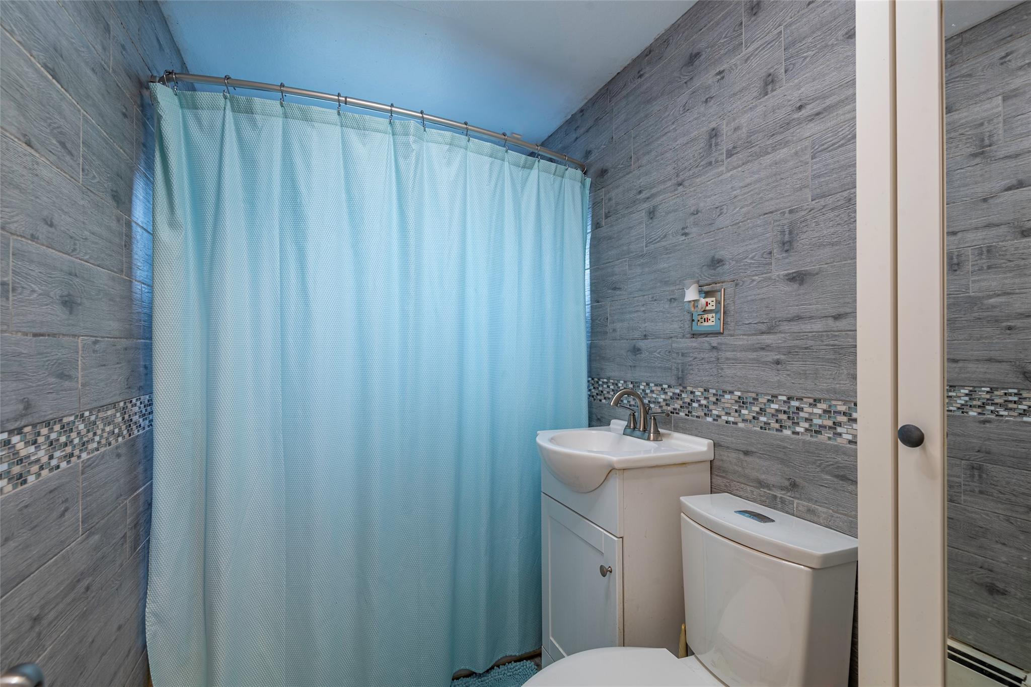 22 Lowland Road Levittown, NY 11756 - Photo 18 of 38 Bathroom with tile walls, a shower with shower curtain, and vanity