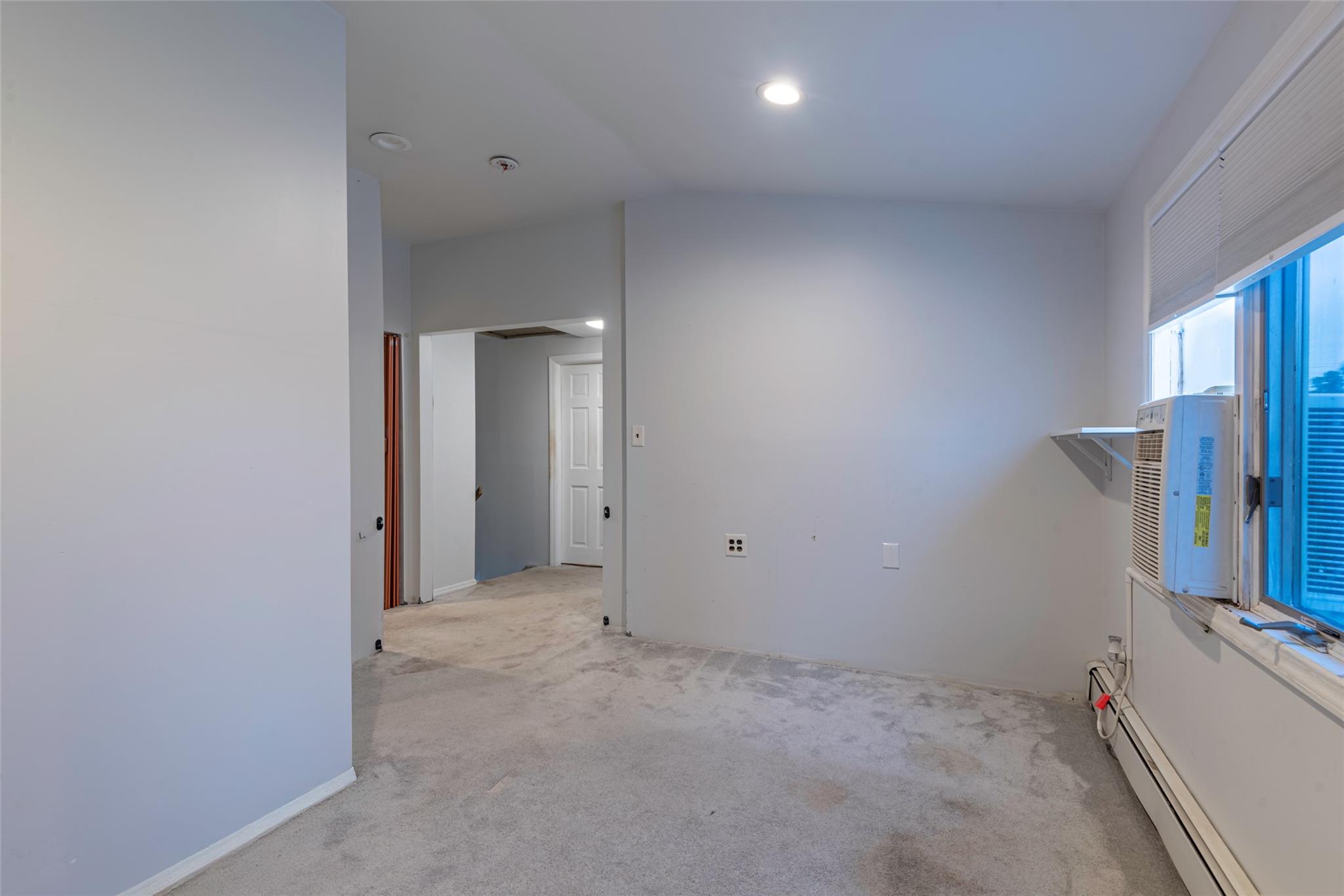 22 Lowland Road Levittown, NY 11756 - Photo 22 of 38 Spare room featuring light carpet, a baseboard radiator, lofted ceiling, and cooling unit