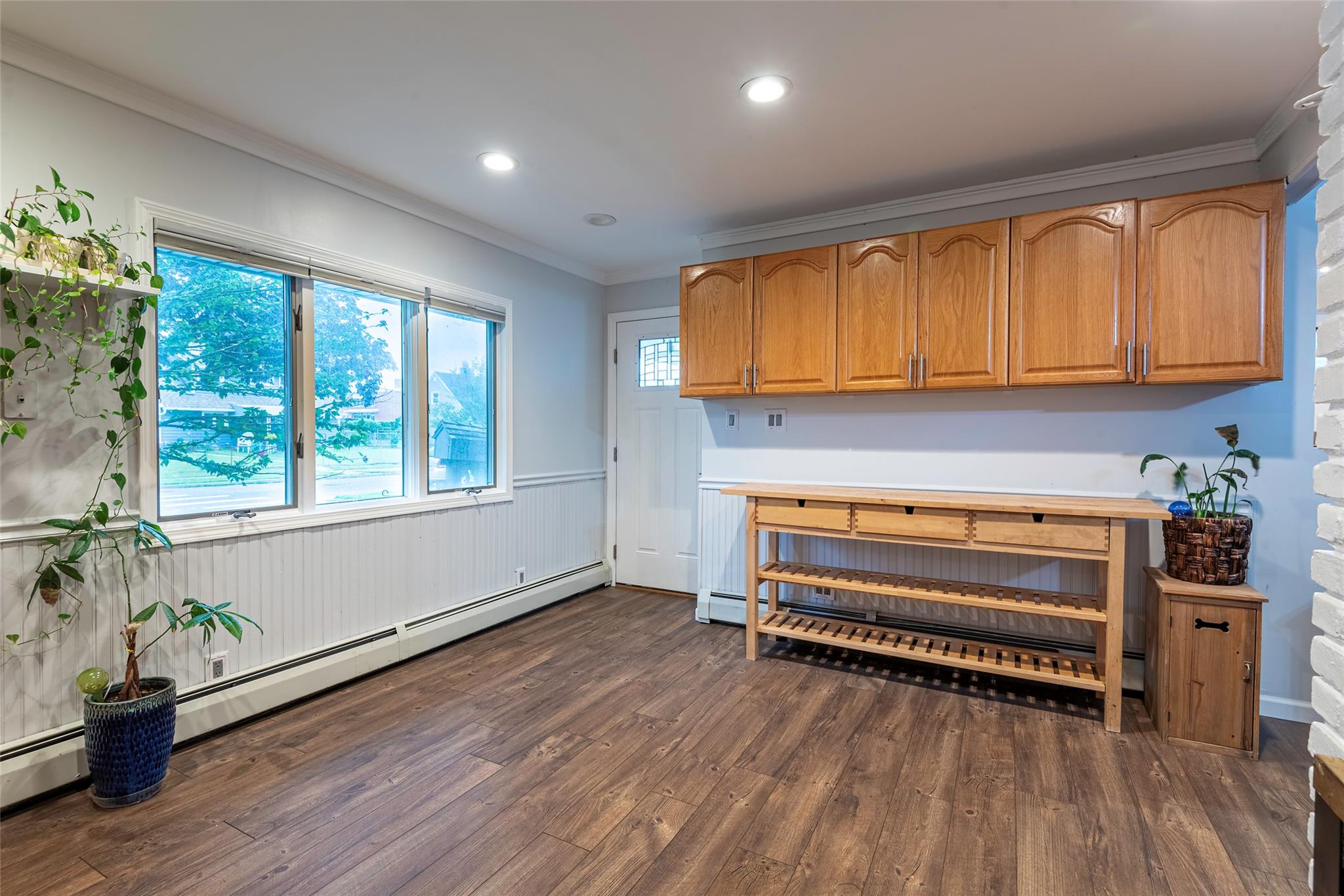 22 Lowland Road Levittown, NY 11756 - Photo 6 of 38 Kitchen with crown molding, dark wood-type flooring, baseboard heating, wainscoting, and light countertops