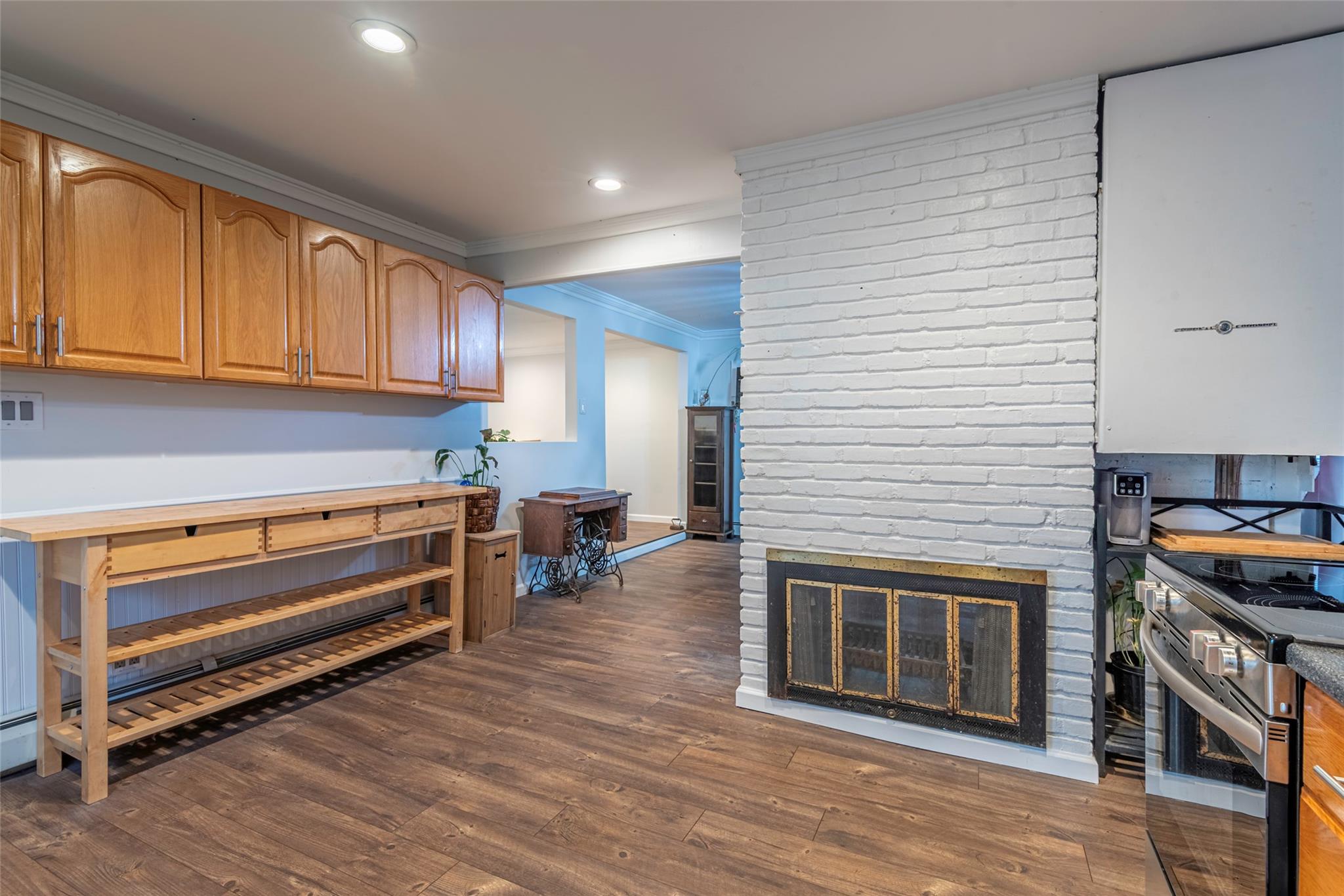 22 Lowland Road Levittown, NY 11756 - Photo 7 of 38 Bar featuring crown molding, dark wood finished floors, stainless steel electric stove, recessed lighting, and a fireplace