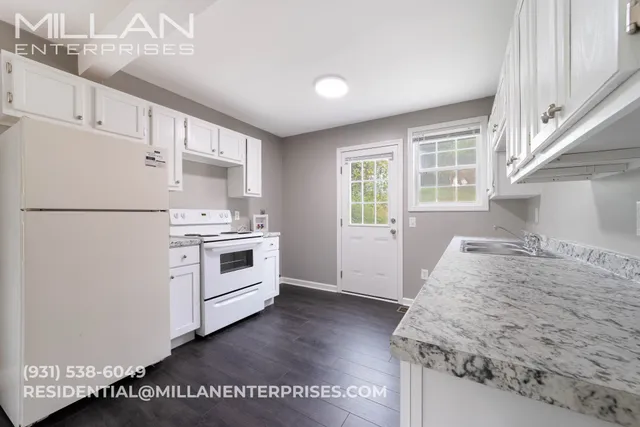 a kitchen with granite countertop white cabinets and white appliances