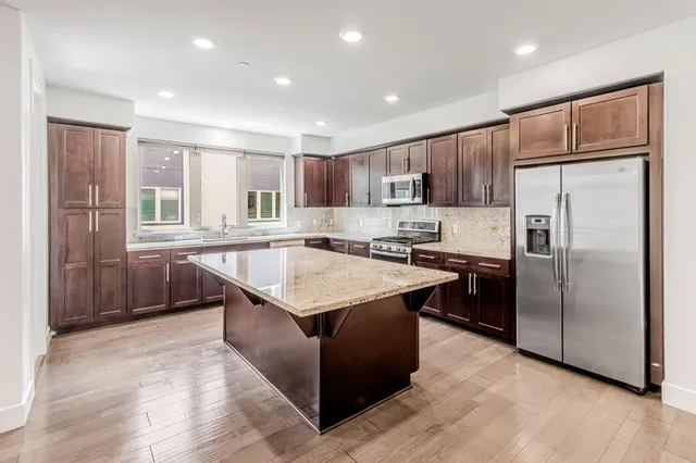 a kitchen with stainless steel appliances granite countertop a refrigerator a sink a stove a microwave and island