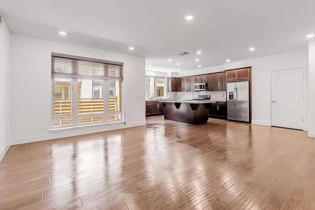 a view of kitchen with refrigerator stove and wooden floor