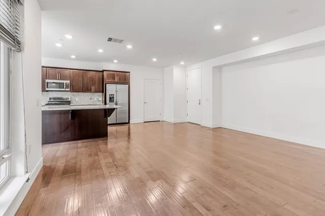 a view of kitchen with stainless steel appliances wooden floor and large window