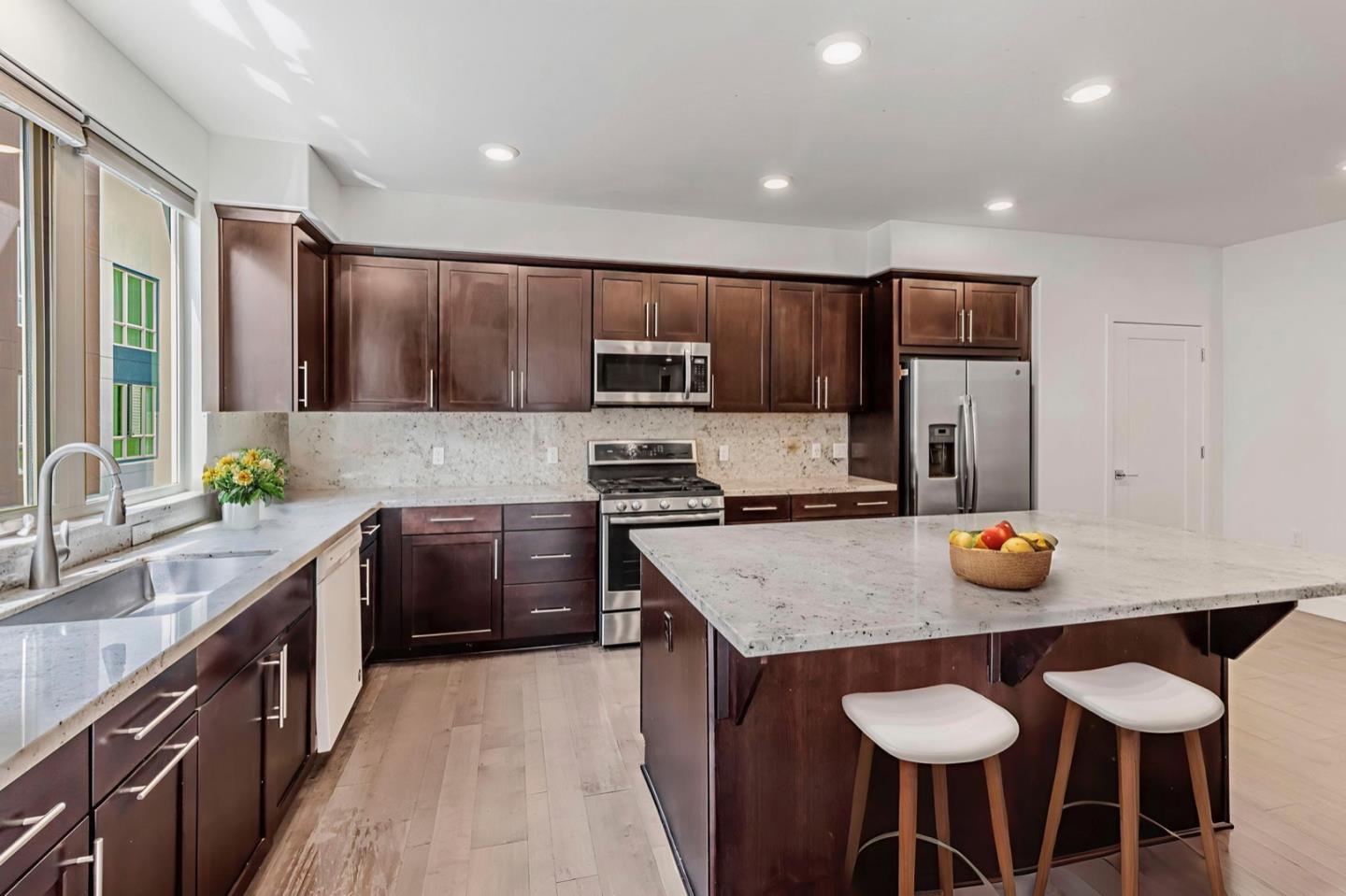 380 Riesling Avenue, Unit 21 Milpitas, CA 95035 - Photo 9 of 37 a kitchen with stainless steel appliances granite countertop a sink a stove a refrigerator cabinets and chairs