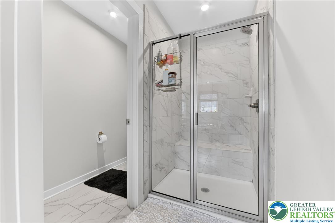 3952 Orth Street Bethlehem, PA 18020 - Photo 27 of 60 A well-lit primary bathroom with sleek, marble-patterned tile and a clear glass shower enclosure awaits.