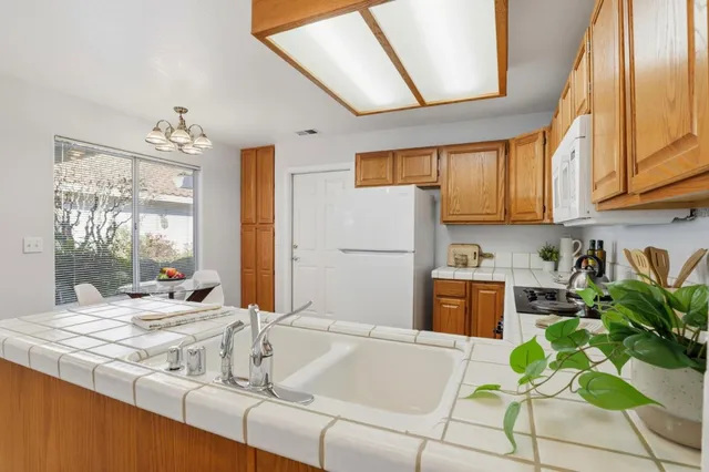 a kitchen with stainless steel appliances granite countertop a refrigerator a sink dishwasher a stove and white countertops with wooden floor