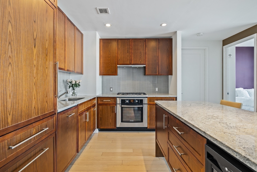 580 Washington Street, Unit PH5 Boston, MA 02111 - Photo 11 of 37 a kitchen with stainless steel appliances granite countertop a sink and cabinets