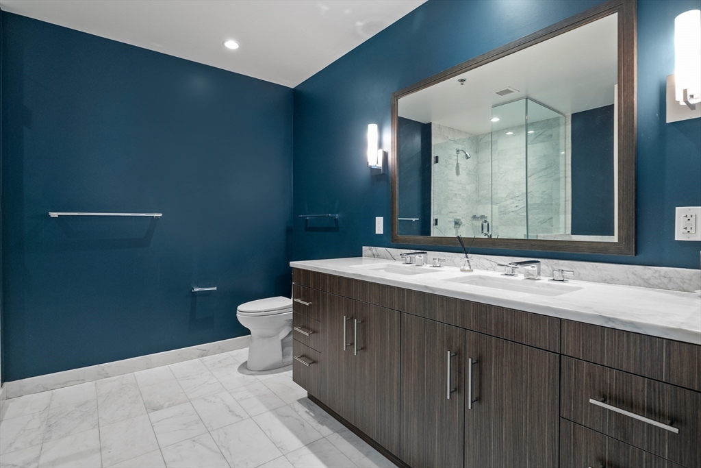 580 Washington Street, Unit PH5 Boston, MA 02111 - Photo 14 of 37 a bathroom with a double vanity sink toilet and a mirror