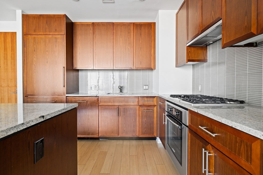 580 Washington Street, Unit PH5 Boston, MA 02111 - Photo 10 of 37 a kitchen with granite countertop cabinets stainless steel appliances and a sink