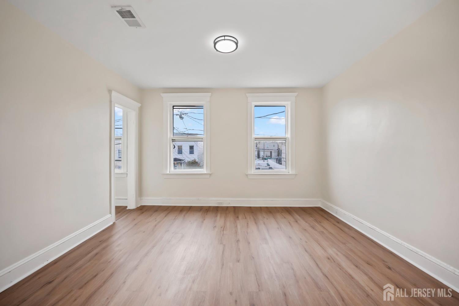 264 Barclay Street Perth Amboy, NJ 08861 - Photo 21 of 45 an empty room with wooden floor and windows