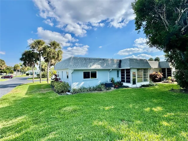 a view of a house with a big yard potted plants and large tree