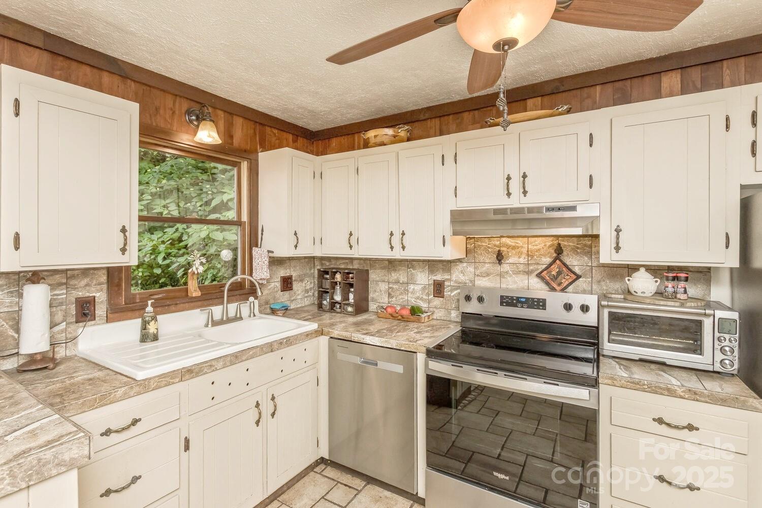 557 Tumbling Fork Road Waynesville, NC 28785 - Photo 7 of 44 a kitchen with a sink stove and white cabinets