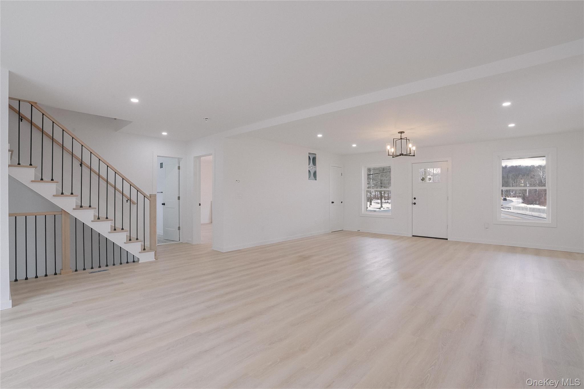 17 Maple Street Beacon, NY 12508 - Photo 9 of 35 Unfurnished living room with light wood finished floors, recessed lighting, stairway, and a chandelier