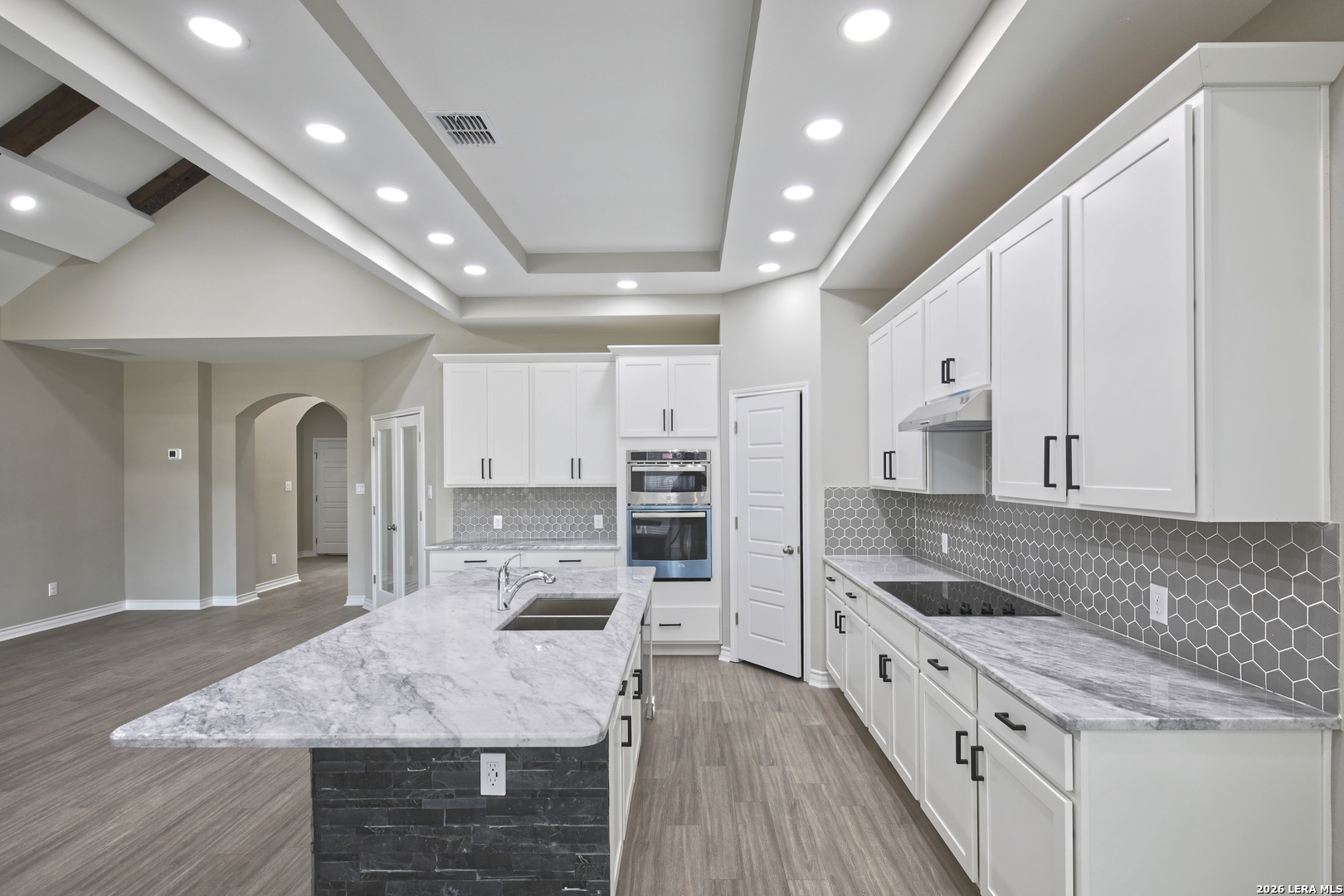 918 Marbach Road Somerset, TX 78069 - Photo 14 of 36 a large kitchen with kitchen island a stove a sink a refrigerator and white cabinets with wooden floor
