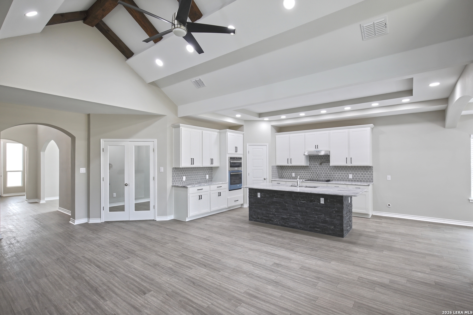 918 Marbach Road Somerset, TX 78069 - Photo 8 of 36 a large kitchen with kitchen island a stove a sink dishwasher a refrigerator and white cabinets with wooden floor