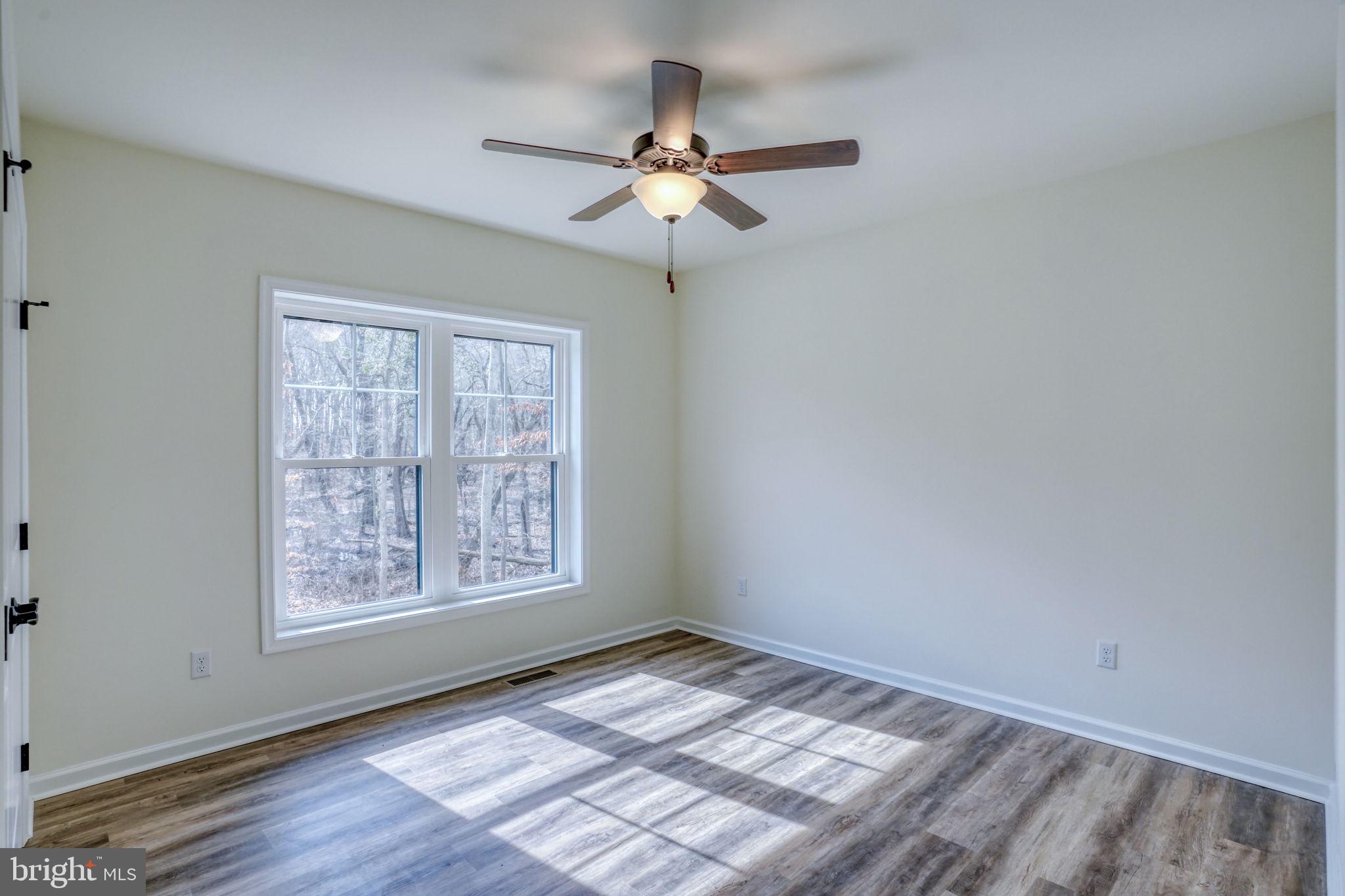156 Pratts Branch Road Felton, DE 19943 - Photo 21 of 35 an empty room with wooden floor chandelier fan and windows