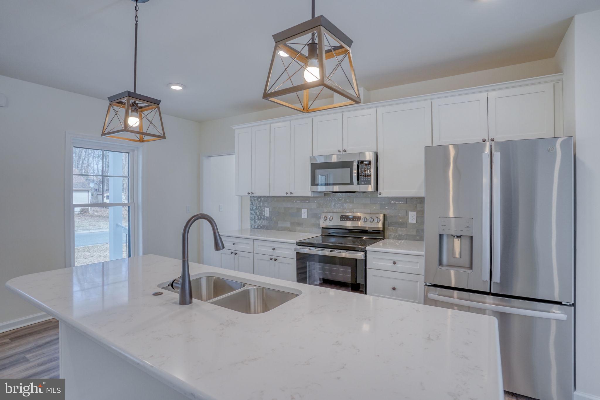 156 Pratts Branch Road Felton, DE 19943 - Photo 9 of 35 a kitchen with stainless steel appliances a sink a stove a refrigerator cabinets a dining table and chairs