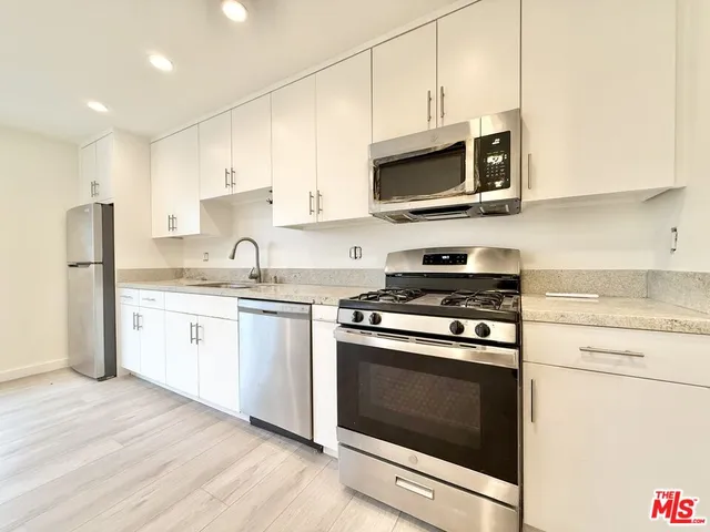 a kitchen with stainless steel appliances white cabinets a stove top oven a sink and dishwasher