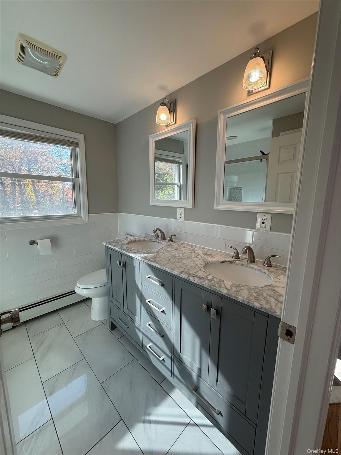 a bathroom with a granite countertop sink a toilet and mirror