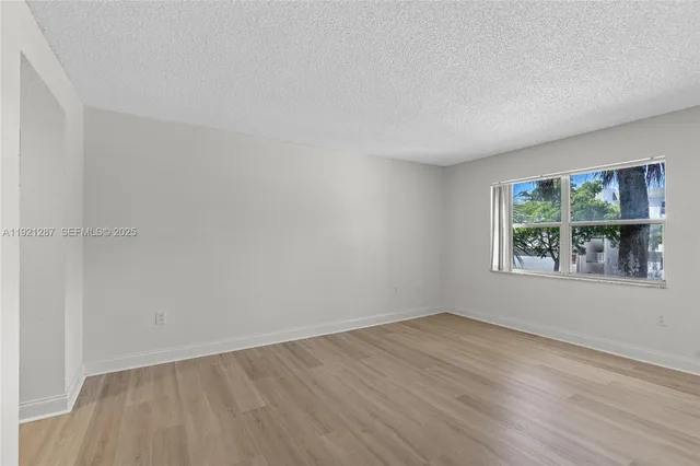 an empty room with wooden floor and window