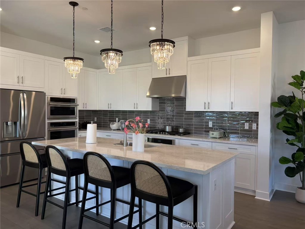313 Terrapin Irvine, CA 92618 - Photo 3 of 14 a kitchen with stainless steel appliances granite countertop a stove a refrigerator a sink a dining table and chairs with wooden floor