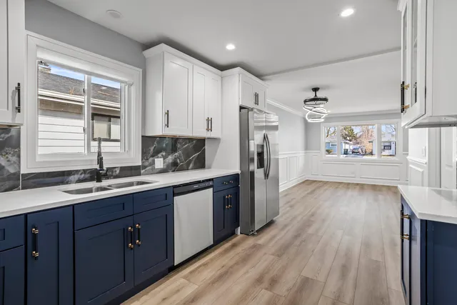 a kitchen with stainless steel appliances granite countertop a refrigerator a sink dishwasher and wooden cabinets with wooden floor