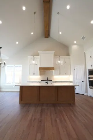 a large kitchen with kitchen island a sink wooden floor and outdoor view