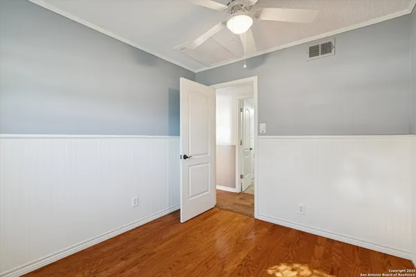 an empty room with a ceiling fan and wooden floor