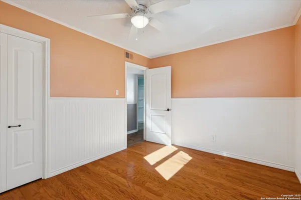 a view of empty room with wooden floor and fan