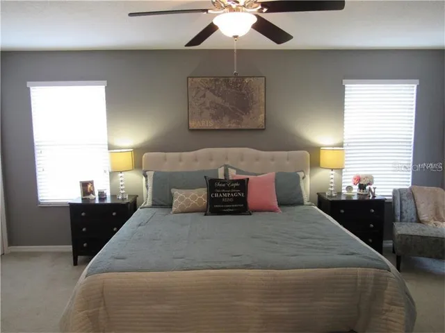 a large bed sitting in a bedroom next to a window and a chandelier