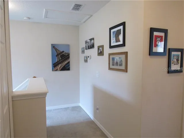 a hallway with painting and a refrigerator
