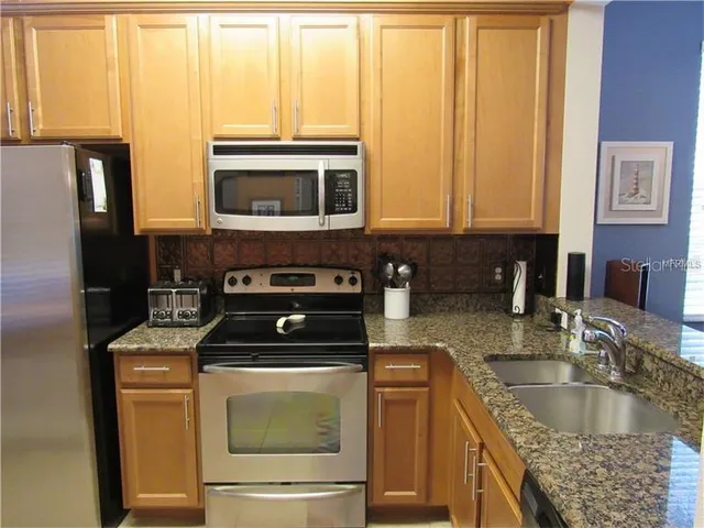 a kitchen with granite countertop a sink a stove and a microwave