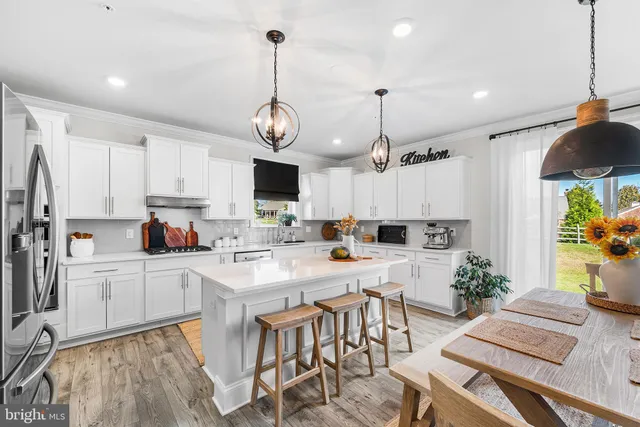 a kitchen with white cabinets stainless steel appliances and dining table