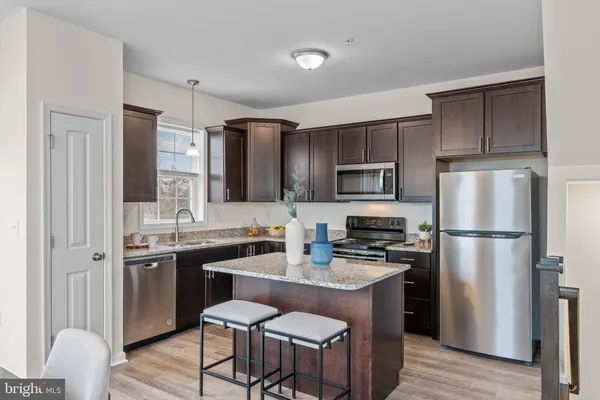 a kitchen with stainless steel appliances granite countertop a refrigerator a stove a sink a dining table and chairs