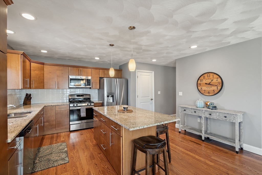 78 Oak Street, Unit 78 Clinton, MA 01510 - Photo 2 of 22 a open kitchen with stainless steel appliances granite countertop a stove top oven a sink dishwasher and chairs with wooden floor