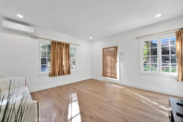 a view of an empty room with a window and wooden floor