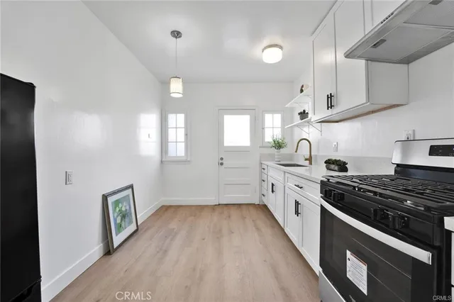 a kitchen with stainless steel appliances a stove a sink and white cabinets