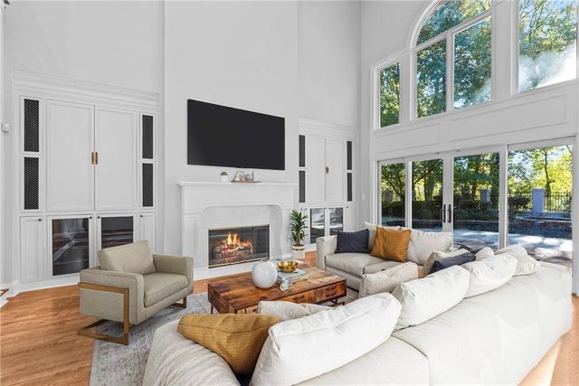 a view of an empty room with wooden floor and a kitchen