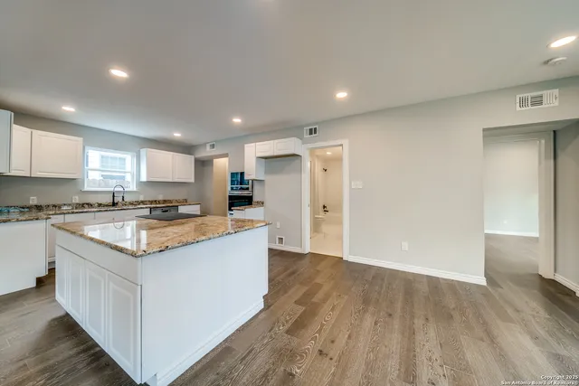 a kitchen with stainless steel appliances granite countertop sink stove refrigerator and cabinets