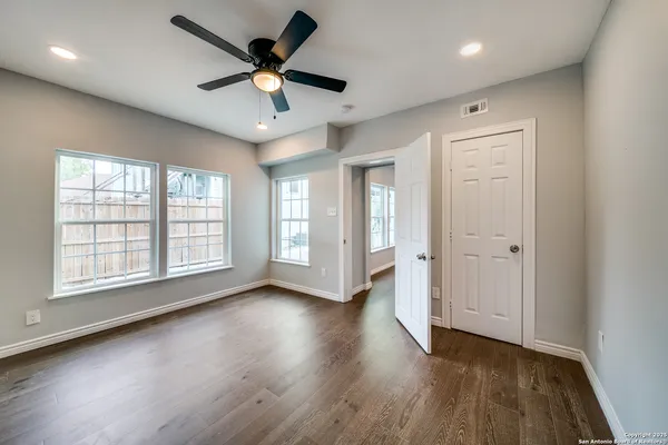 an empty room with wooden floor and windows