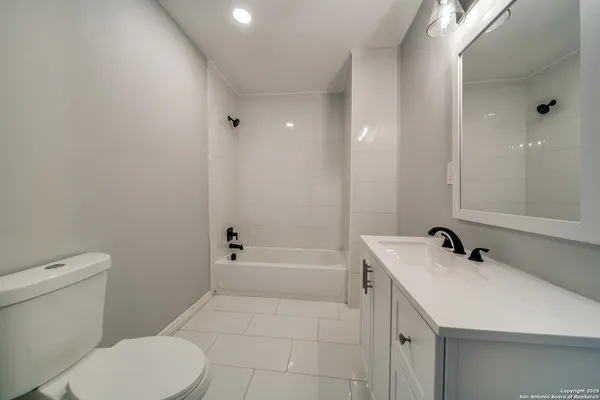 a bathroom with a granite countertop sink a toilet and shower