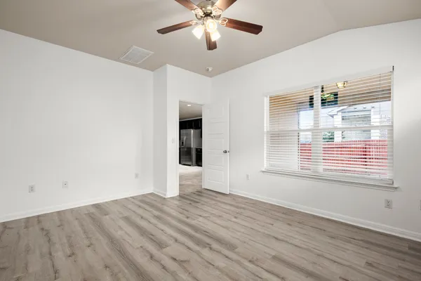 a view of an empty room with wooden floor and a window