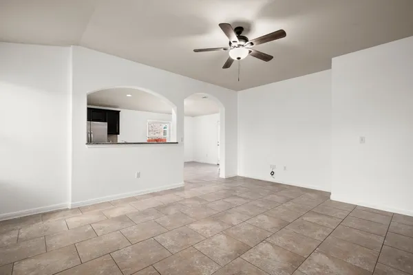 an empty room with chandelier fan and windows