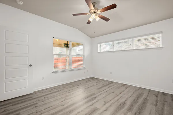a view of empty room with wooden floor and fan