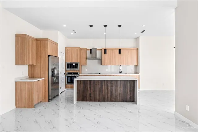 a large white kitchen with stainless steel appliances kitchen island granite countertop a refrigerator and a stove top oven